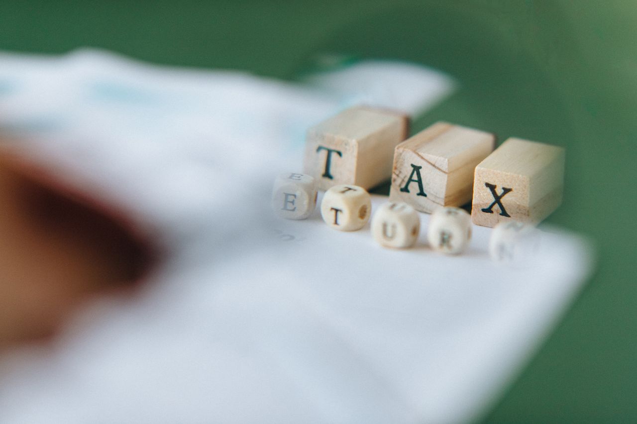 Crafting Captivating Headlines: Your awesome post title goes here Wooden blocks and dice spelling 'Tax Return' on a blurred green background.